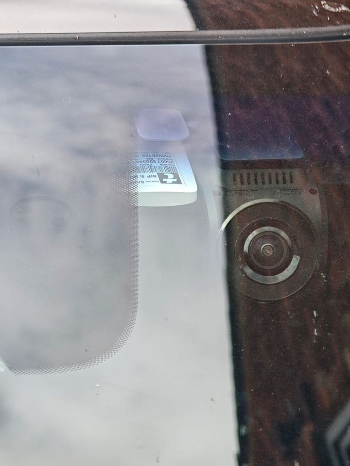 An Emovis toll tag fitted behind a car rear-view mirror